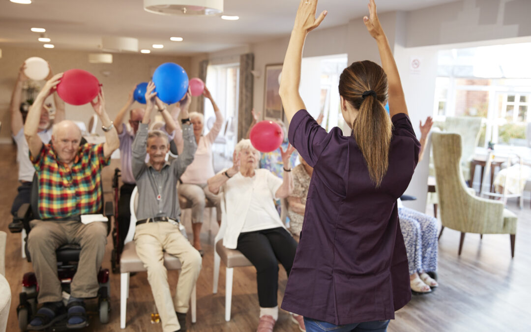 An assisted living staff member leads a group of seniors in a fitness class for what are the benefits of exercise for the elderly blog.