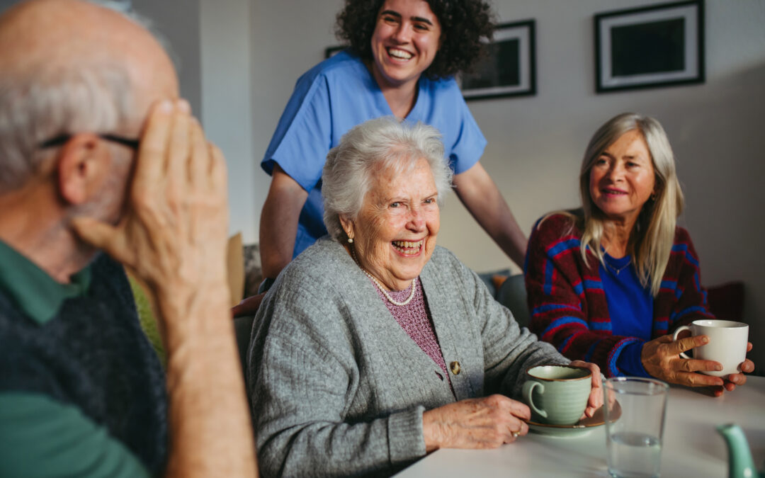 Seniors laugh and have a good time together at the dining room table for celebrating-Older-Americans-Month blog.