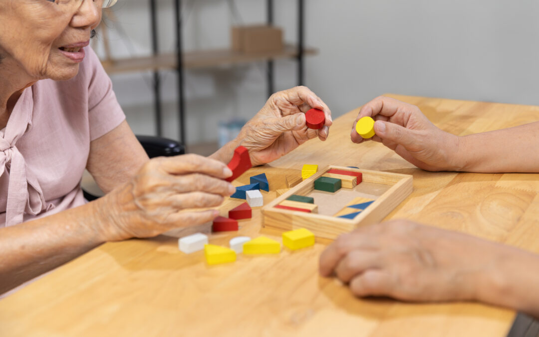 A caregiver and a senior woman play a colorful wooden shape puzzles game for cognitive-health-in-assisted-living blog.